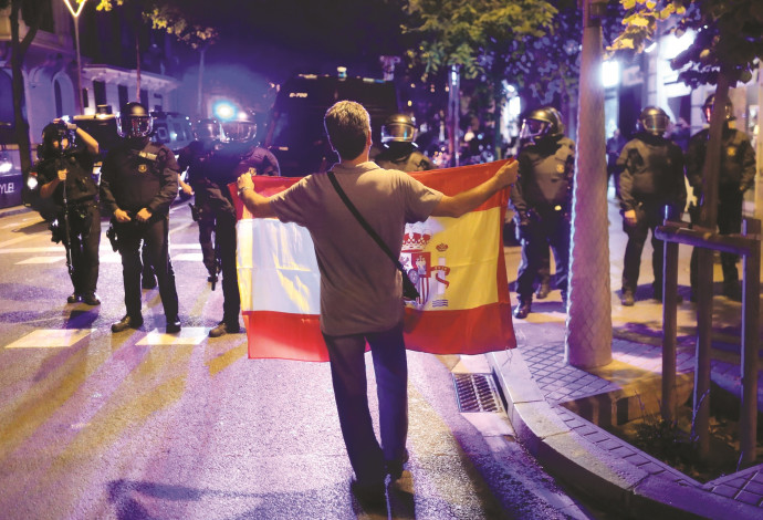 אדם מחזיק דגל קטלוניה מול שוטרים בברצלונה (צילום:  רויטרס)
