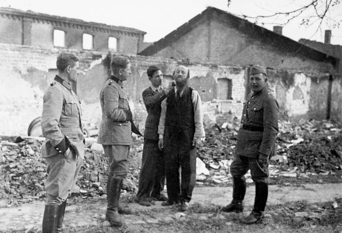 פולני מגלח ליהודי את שערו בפני חיילים גרמנים, 1939 (צילום:  Getty images)