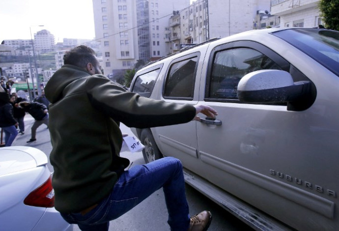מפגין פלסטיני בועט ברכב אמריקאי בבית לחם (צילום:  AFP)
