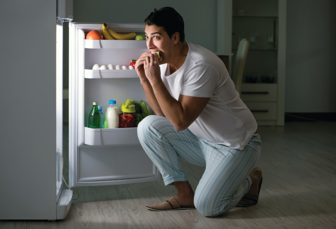 גבר אוכל מול המקרר בלילה, אילוסטרציה (צילום:  אינג אימג')