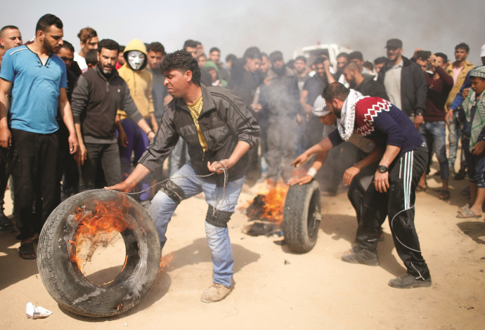פלסטינים מבעירים צמיגים בהפגנה בגבול רצועת עזה (צילום:  רויטרס)