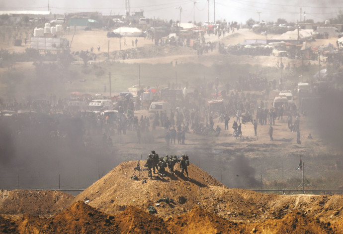 חיילי צה"ל מול מפגינים פלסטינים בגדר רצועת עזה (צילום:  רויטרס)