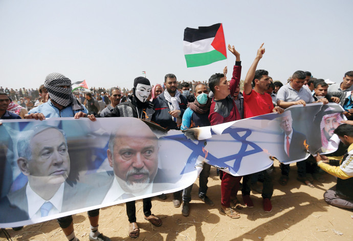 פלסטינים בעזה מפגינים עם תמונות נתניהו וליברמן (צילום:  רויטרס)