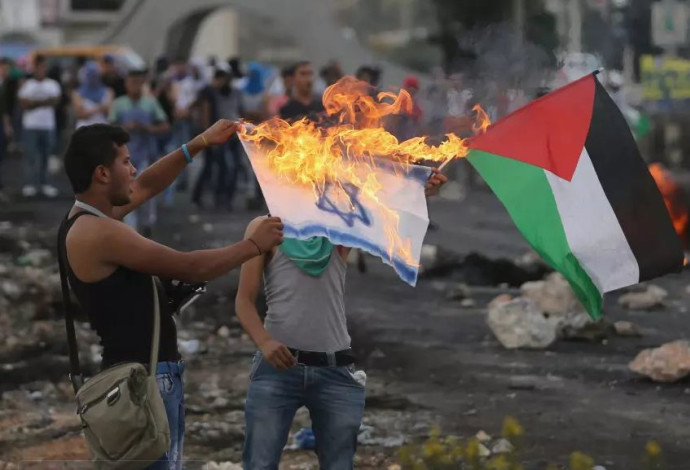 מפגינים פלסטינים שורפים דגל ישראל ליד בית אל  (צילום:  רויטרס)