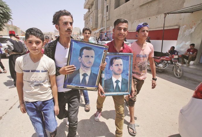תושבי דרעא עם תמונות אסד (צילום:  AFP)