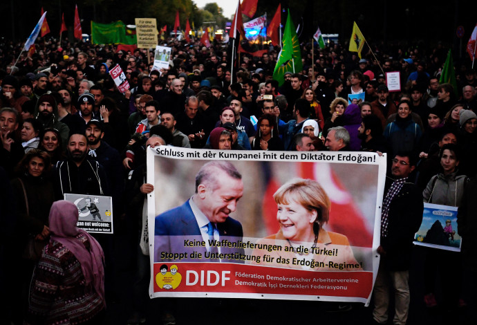 מפגינים מניפים שלט בו כתוב "די לתמיכה הגרמנית בארדואן" (צילום:  AFP)