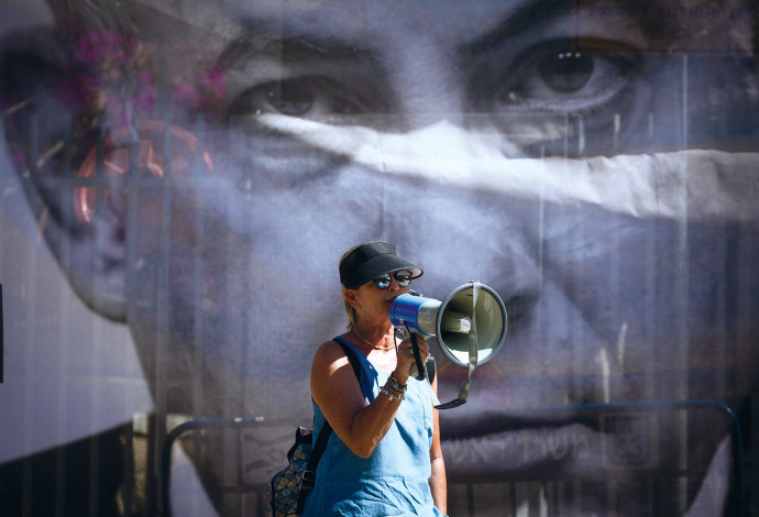 מפגינה מול פוסטר עם תמונתו של בנימין נתניהו (צילום:  יונתן זינדל, פלאש 90)