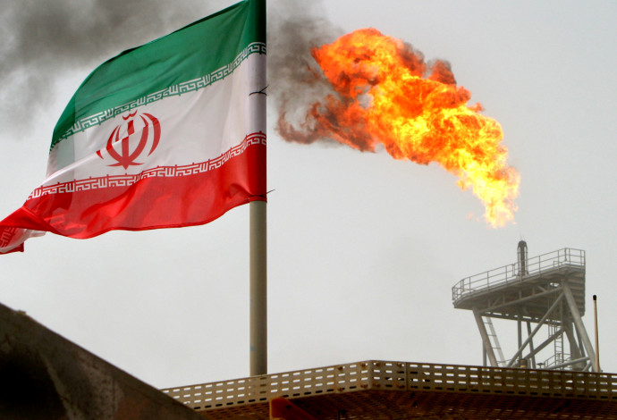 דגל איראן על רקע מתקן ייצור נפט במפרץ הפרסי (צילום:  רויטרס)