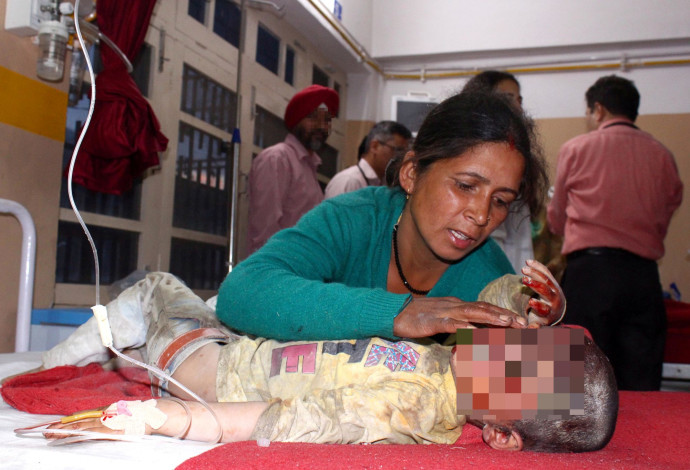 אם עם בנה שנפצע בתאונה בצפון הודו (צילום:  רויטרס)