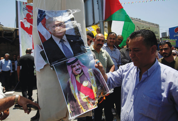 פלסטיני בחברון שורף תמונות של טראמפ ושל מנהיג בחריין (צילום:  רויטרס)