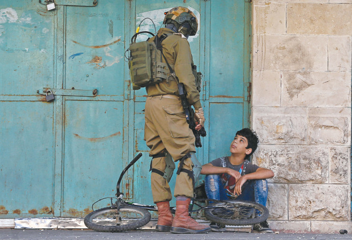 חייל צה"ל ונער פלסטיני (צילום:  רויטרס)