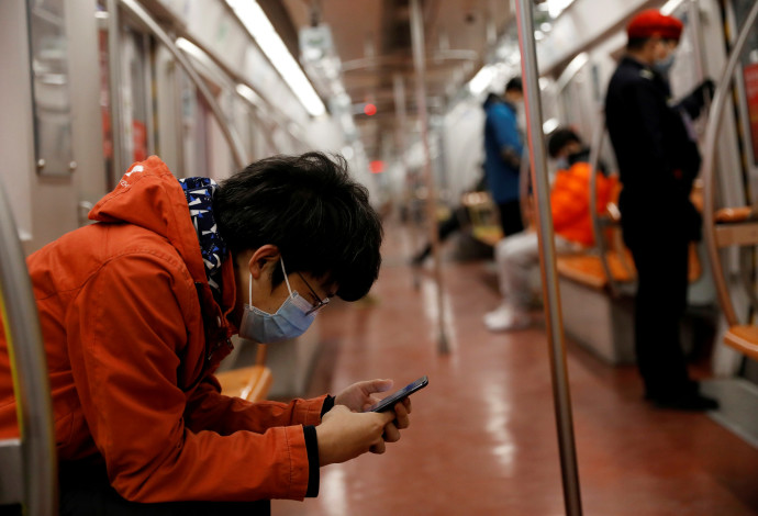 נוסע לובש מסיכה ברכבת בבייג'ינג  (צילום:  REUTERS/Carlos Garcia Rawlins)