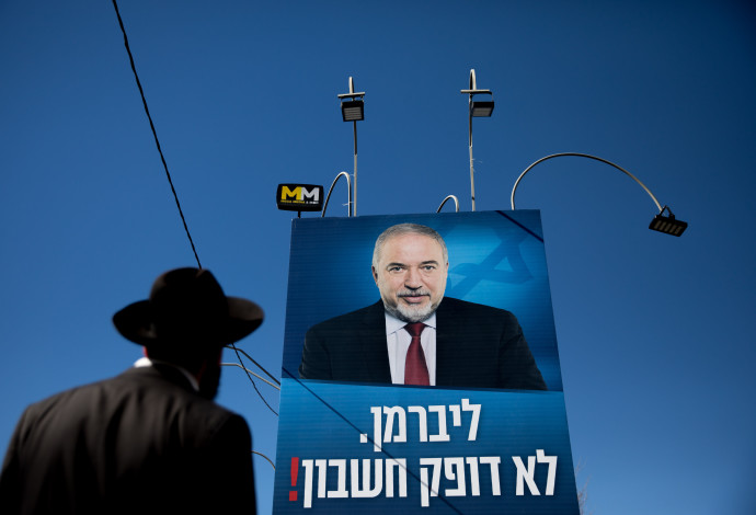 חרדי מביט על שלט קמפיין של מפלגת ישראל ביתנו (צילום:  יונתן זינדל, פלאש 90)