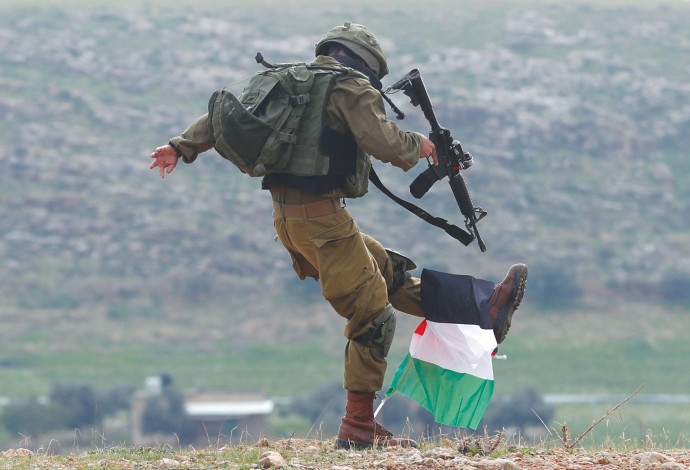חייל צה"ל בועט בדגל פלסטיני (צילום:  רויטרס)