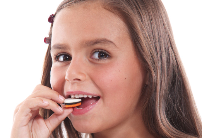 ילדה אוכלת ממתקים (אילוסטרציה) (צילום:  אינג אימג')