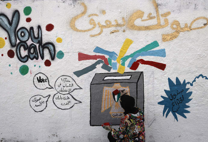 פלסטינית לצד גרפיטי בנושא הבחירות  (צילום:  גטיאימג'ס)