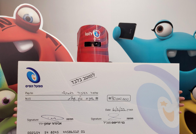 הזוכה ב-80 מיליון בלוטו מקבל את הפרס (צילום:  מפעל הפיס)