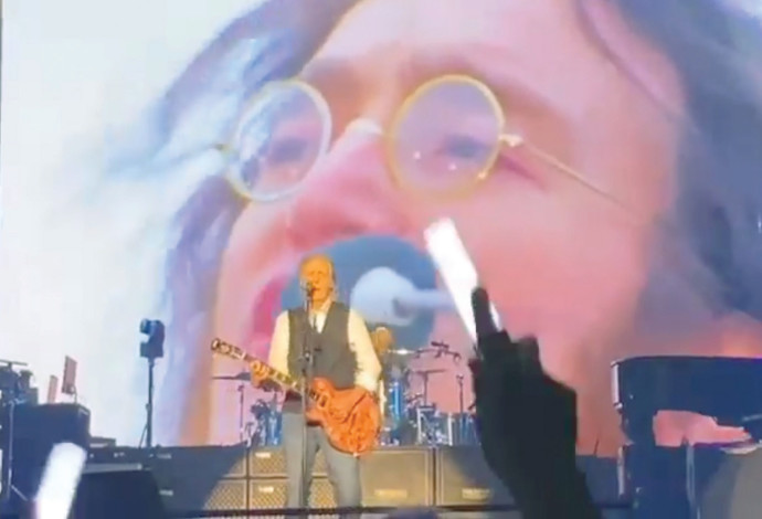 פול מקרטני בהופעה עם ג'ון לנון על המסך (צילום:  צילום מסך)
