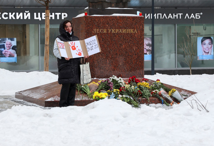 מפגינה מחזיקה שלט מחאה לצד אנדרטה למשוררת אוקראינית במוסקבה (צילום:   REUTERS/Stringer)