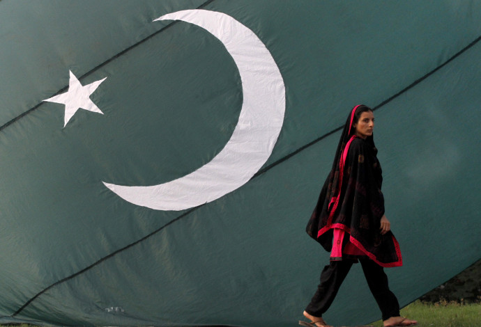 אישה עוברת ליד דגל פקיסטן (צילום:  רויטרס)