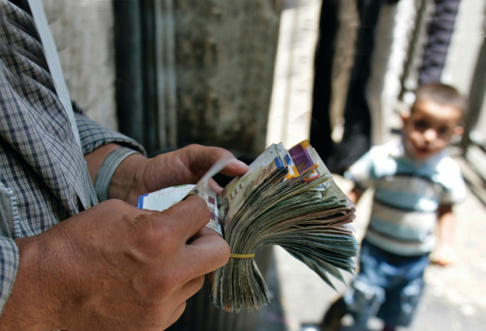 מחליף מטבעות פלסטיני סופר כסף ברחוב ברמאללה  (צילום:  רויטרס)