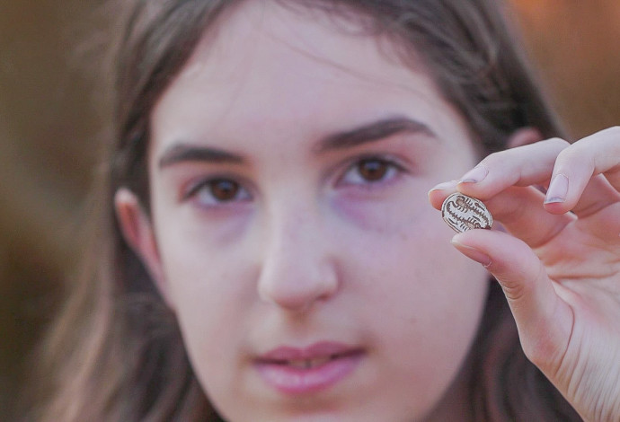 הקמיע שעליו סימן העקרב בידה של דפנה פילשטיינר (צילום:  אמיל אלג'ם, רשות העתיקות)