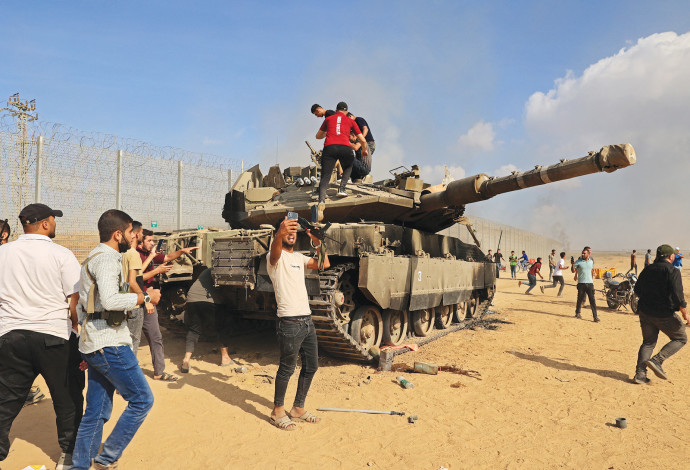 פלסטינים פורצים את גדר עזה, נעמדים על טנק. השבעה באוקטובר (צילום:  SAID KHATIB.GettyImages)