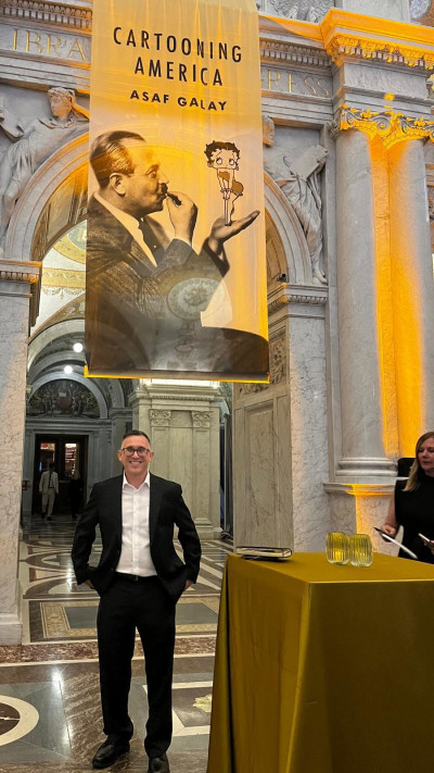 אסף גלאי על רקע כרזת הסרט בטקס