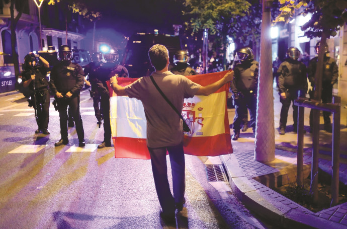 אדם מחזיק דגל קטלוניה מול שוטרים בברצלונה (צילום: רויטרס)