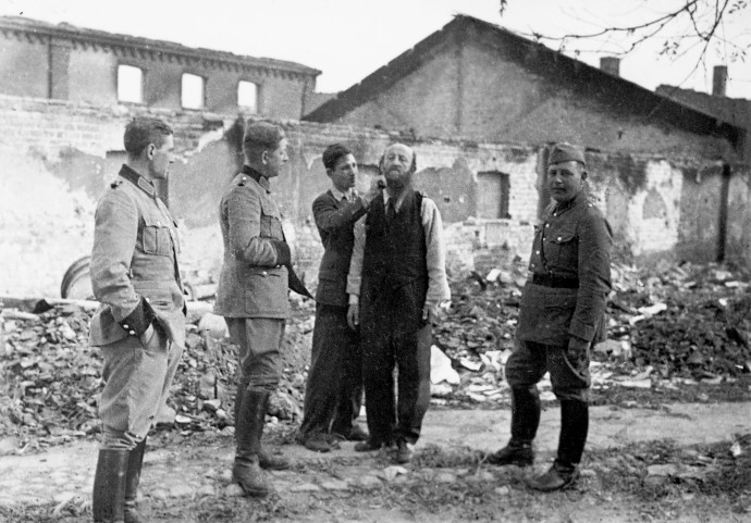 פולני מגלח ליהודי את שערו בפני חיילים גרמנים, 1939 (צילום: Getty images)