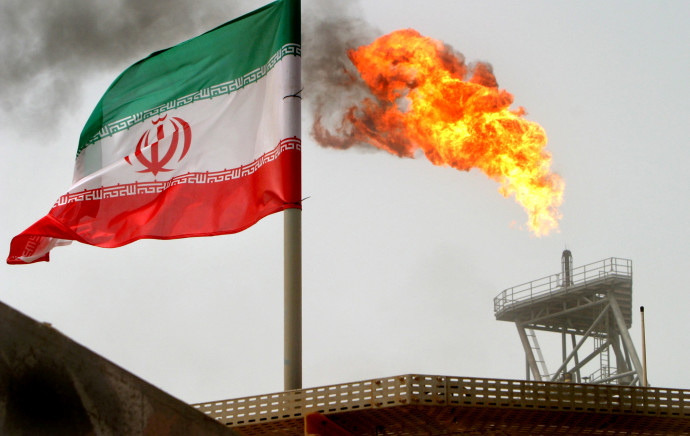 דגל איראן על רקע מתקן ייצור נפט במפרץ הפרסי (צילום: רויטרס)
