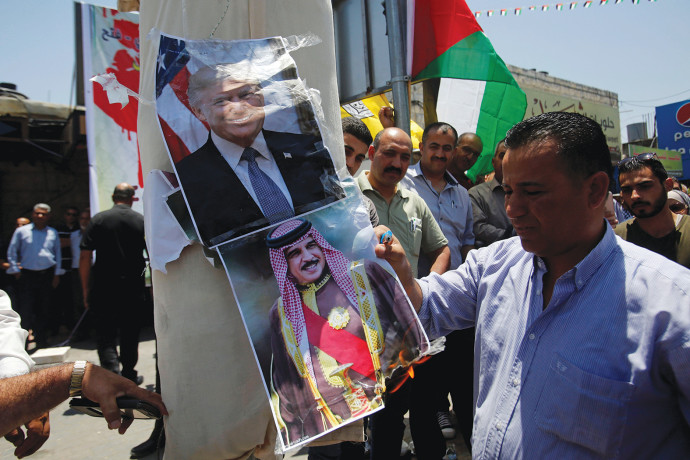 פלסטיני בחברון שורף תמונות של טראמפ ושל מנהיג בחריין (צילום: רויטרס)