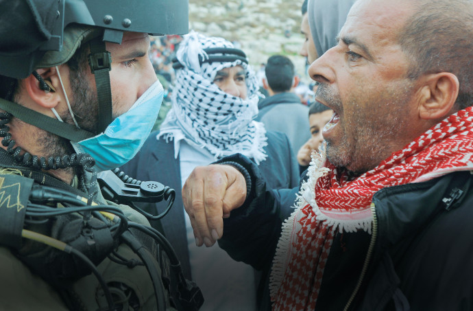 פלסטיני מול חייל צה"ל (צילום: רויטרס)