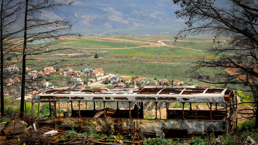 אוטובוס שרוף על רקע של מטולה (צילום: Chen Leopold/Flash90)