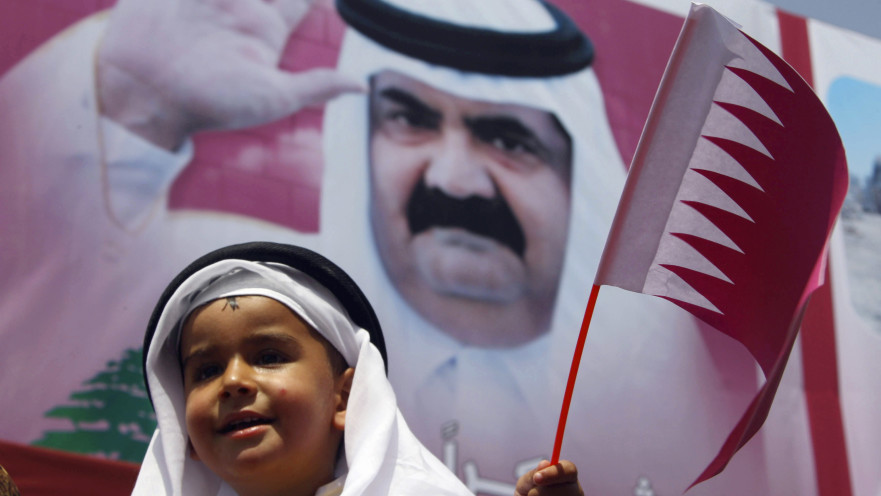 ילד מחזיק דגל קטאר על רקע תמונת האמיר