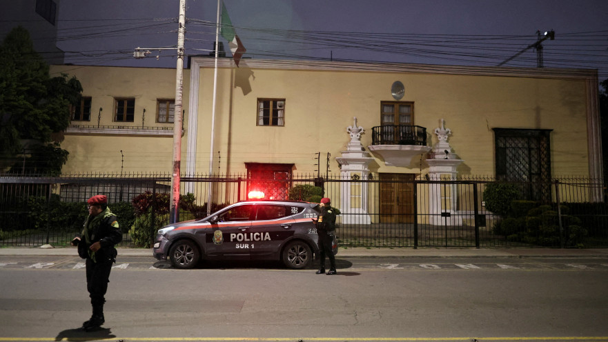 שוטרים פרואנים עומדים סמוך לניידת משטרה מחוץ לשגרירות מקסיקו