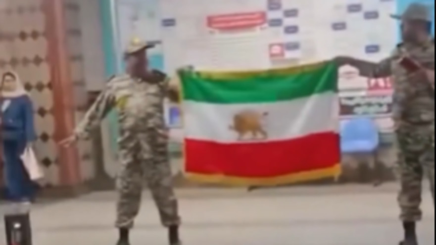 אנשים הלבושים במדי צבא איראן מחזיקים את דגל המדינה לפני המהפכה