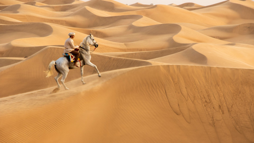 גבר רוכב על סוס במדבריות של עומאן