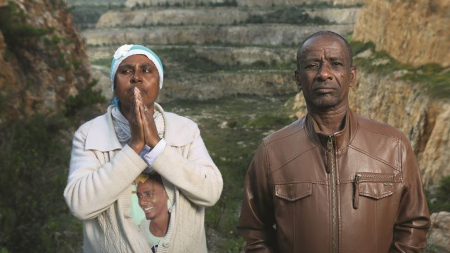 פרנוס וטדלה סלמסה על רקע המקום שבו מצא בנם את מותו
