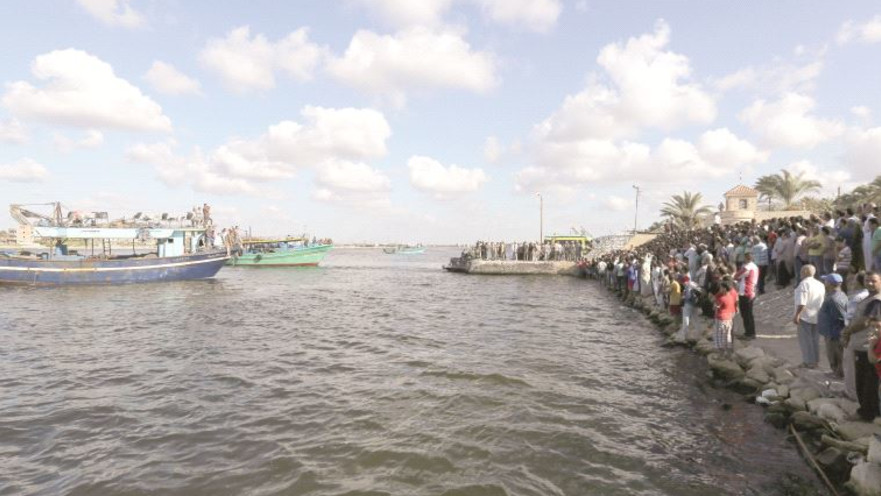 אנשים ממתינים על החוף בזמן החיפוש אחר ניצולים מאסון טביעת הספינה ליד מצרים