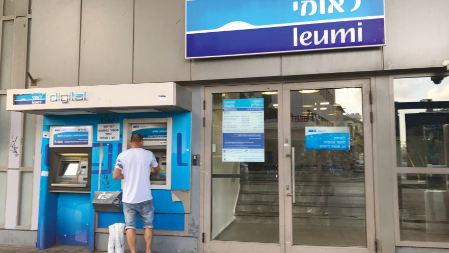 אדם מוציא כסף מכספומט של בנק לאומי