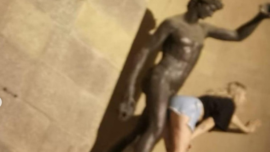 צעירה מתגפפת עם פסל בפירנצה