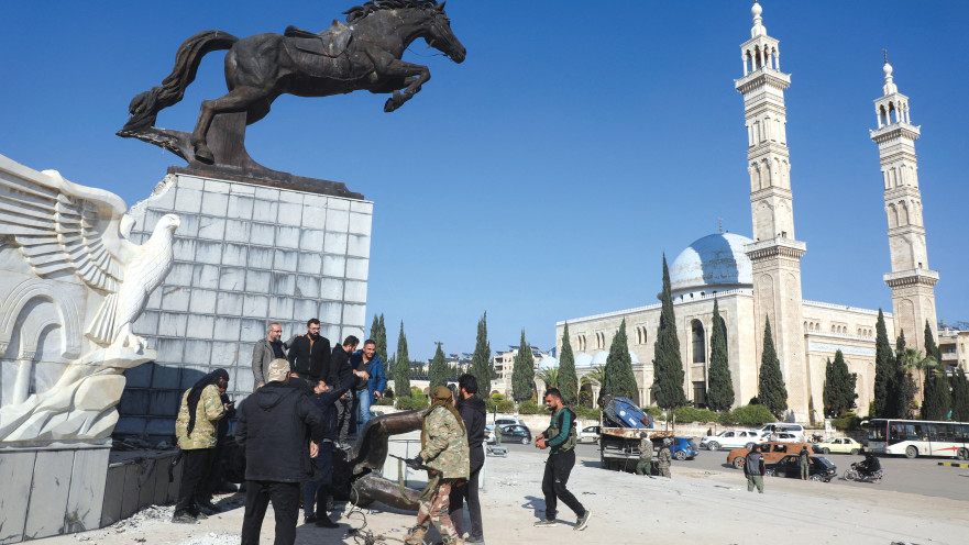לוחמי אופוזיציה סוריה עומדים ליד פסל פגום בחלב