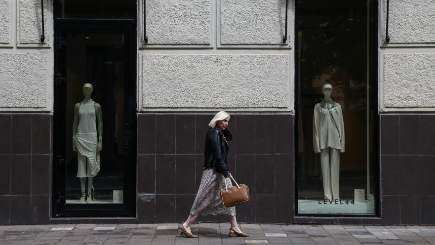 אישה עוברת ליד חנות בגדים במוסקבה, רוסיה