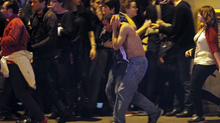 פצוע מחזיק את ראשו מחוץ לאולם בטקלן, בו התרחש הטבח. צילום: רויטרס