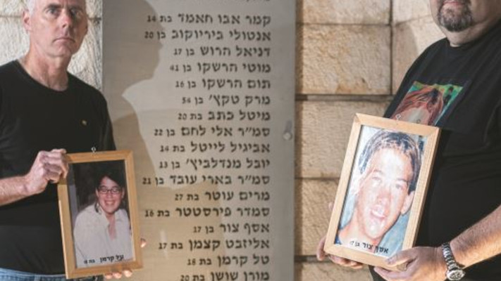 רון קרמן (משמאל) ויוסי צור עם תמונות ילדיהם באנדרטה לזכר נרצחי הפיגוע בקו 37