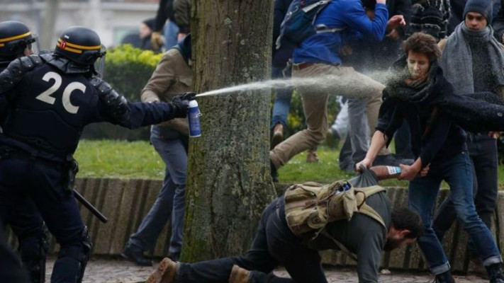 שוטרים צרפתים מתיזים גז מדמיע לעבר מפגינים בליל שבצרפת. צילום: רויטרס