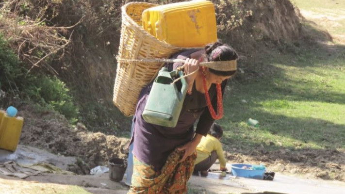 כל ג'ריקן ממולא ב־20 ליטר מים. אישה חוזרת מהבאר שבעמק מתחת לכפר. צילום: סטפני רינת סמית'