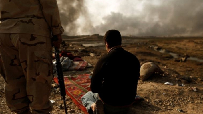 לוחם עיראקי עם שבוי מהמדינה האסלאמית. צילום:רויטרס