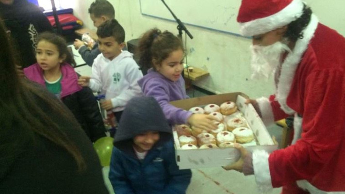 סנטה קלאוס מחלק סופגניות בבית הספר. צילום: עמותת &quot;יד ביד&quot;